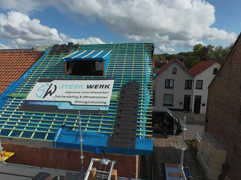 Hellend dak in renovatie met nieuwe tengellatten, onderdakfolie en de banner van Sterkwerk Dakwerken op het dak
