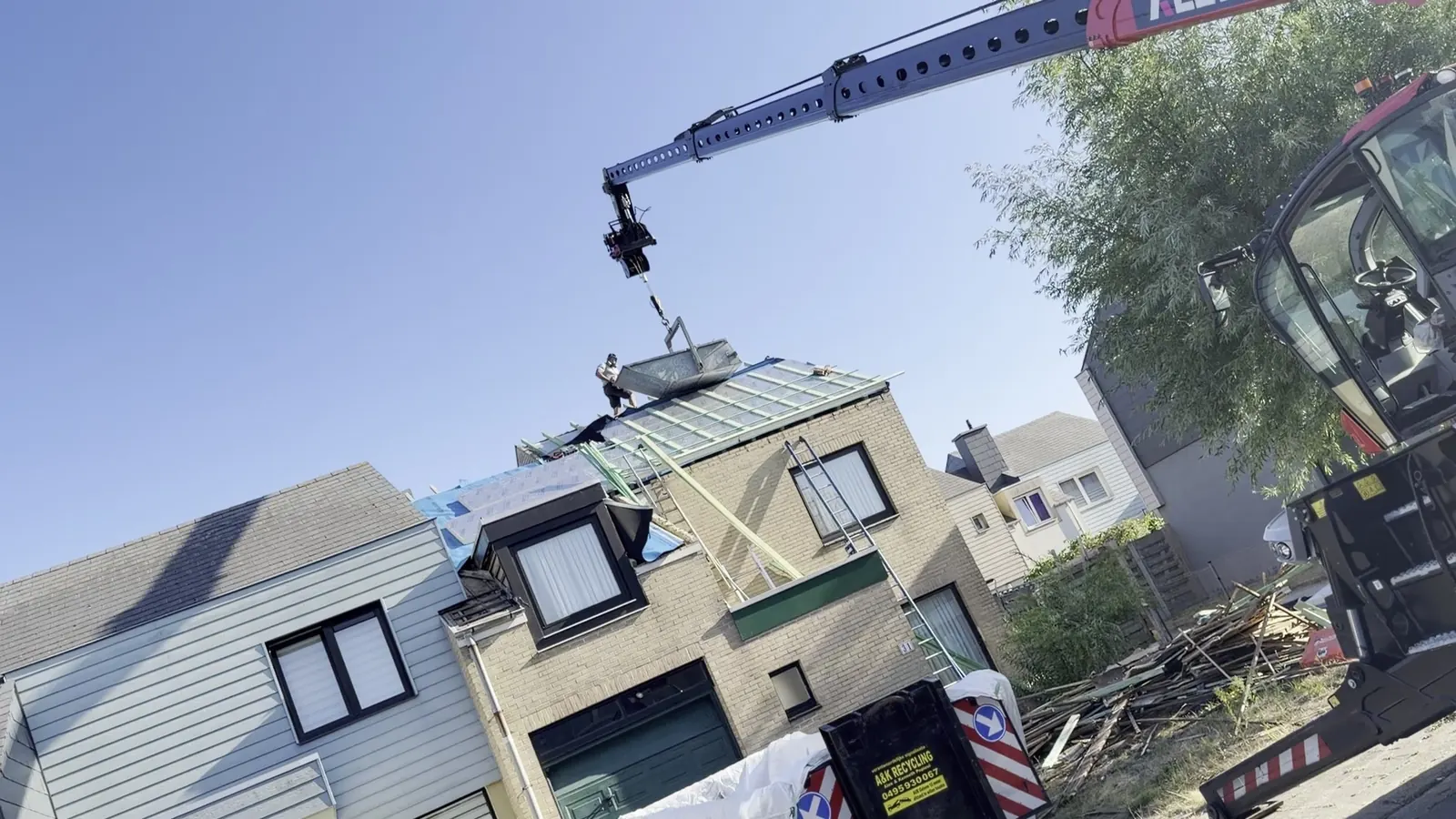 Telekraan hijst materiaal naar het dak tijdens een dakrenovatie