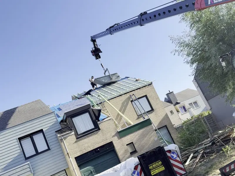 Telekraan hijst materiaal naar het dak tijdens een dakrenovatie