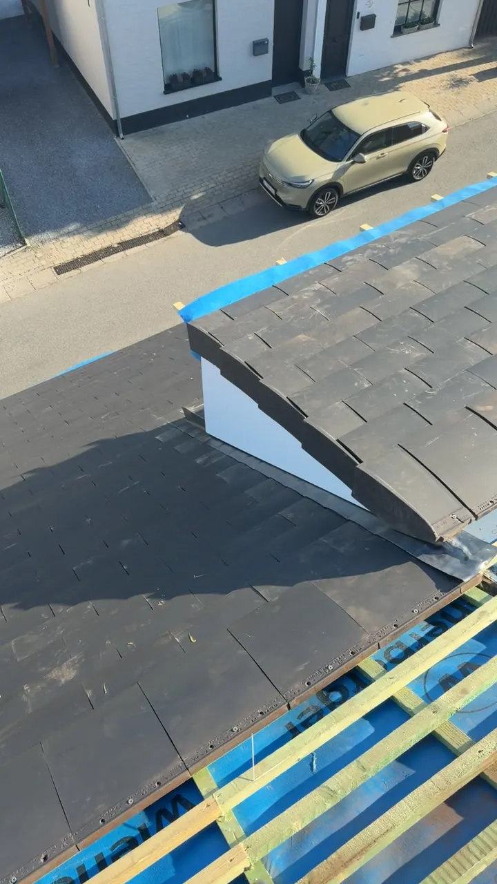 Leien die op tengellatten en blauwe onderdakfolie geplaatst worden op een hellend dak